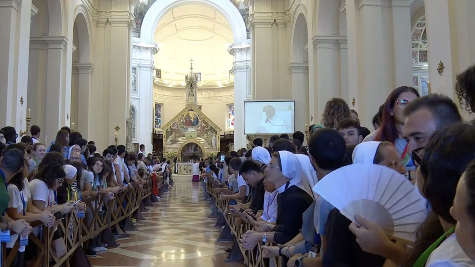 Jóvenes en Asís escuchando al Papa desde el interior de la basílica