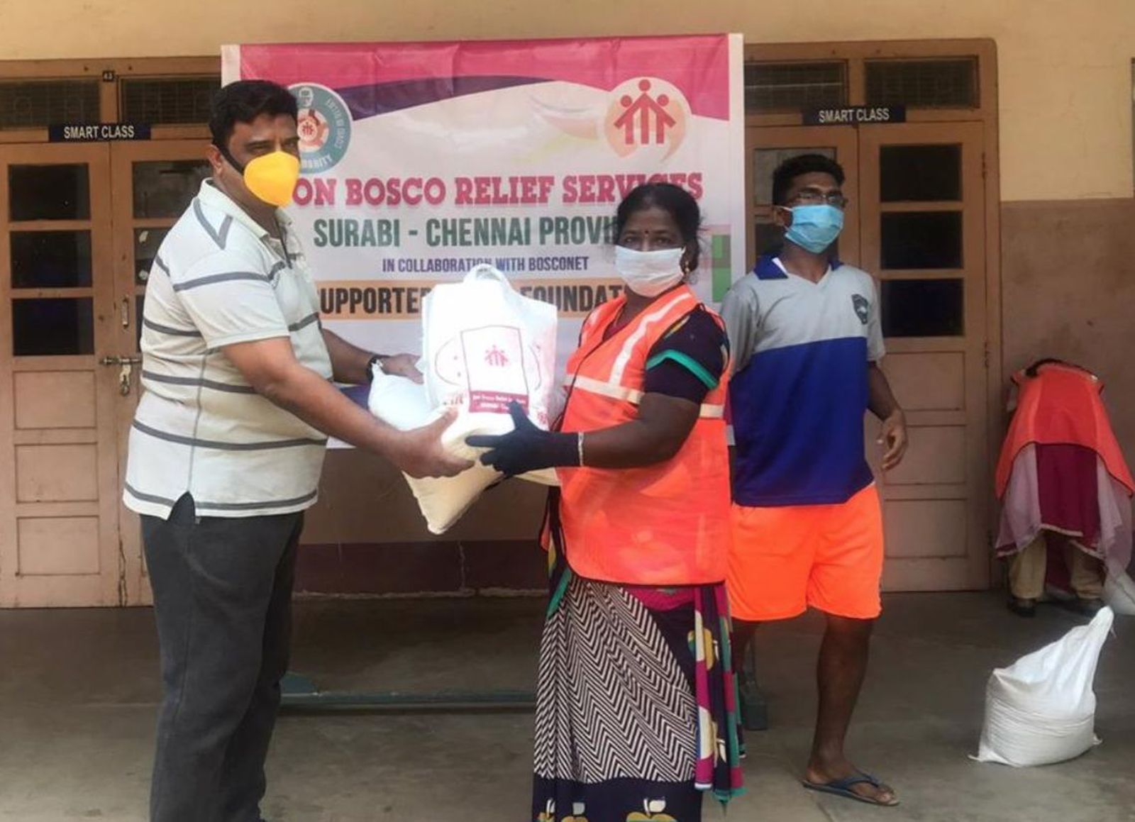 El padre Johnson entrega las bolsas de emergencia a una mujer de los slums. Chennai