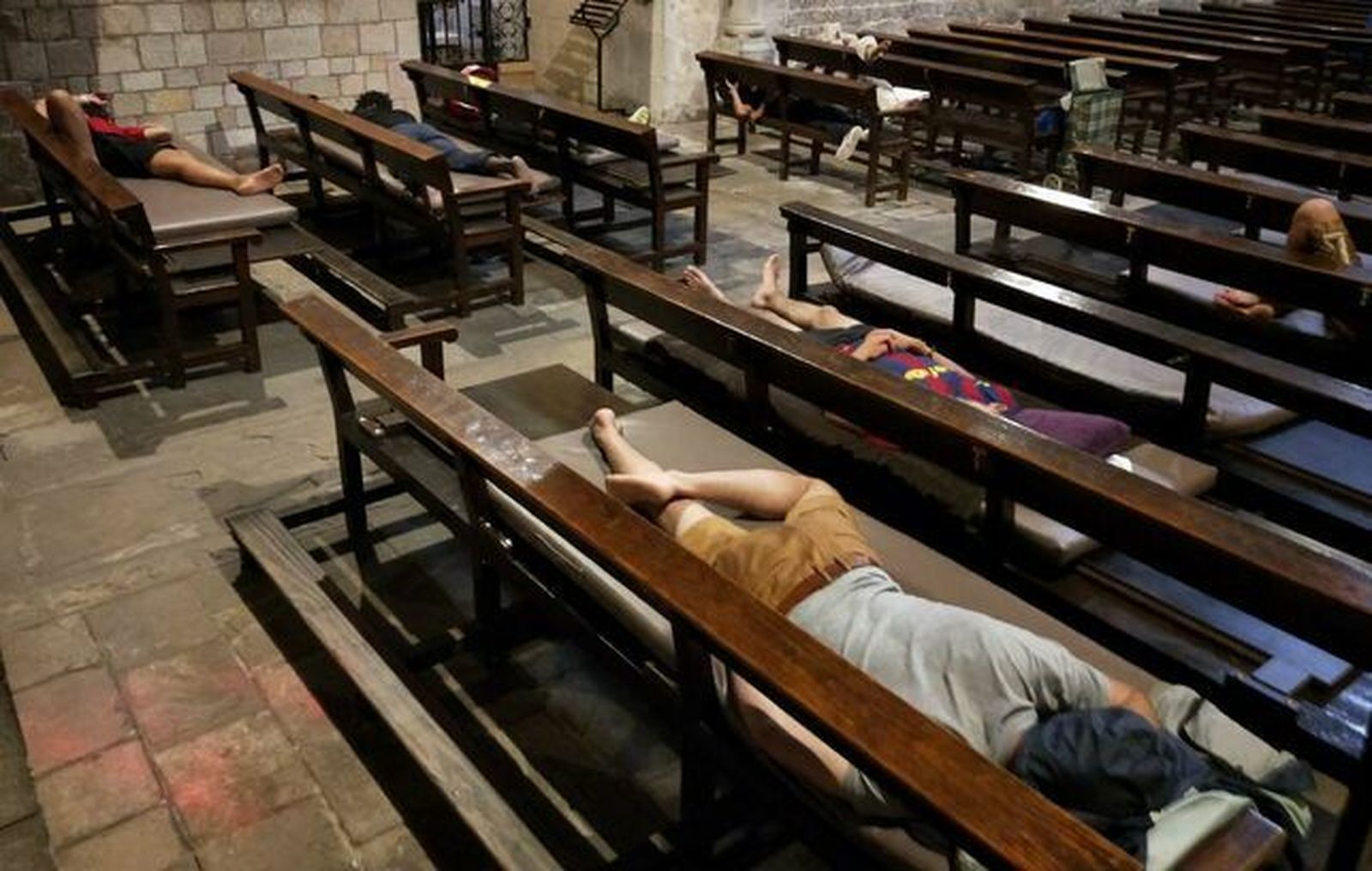 Varios jóvenes migrantes, algunos de ellos menores, durmiendo en los bancos de la Iglesia Santa Anna de Barcelona