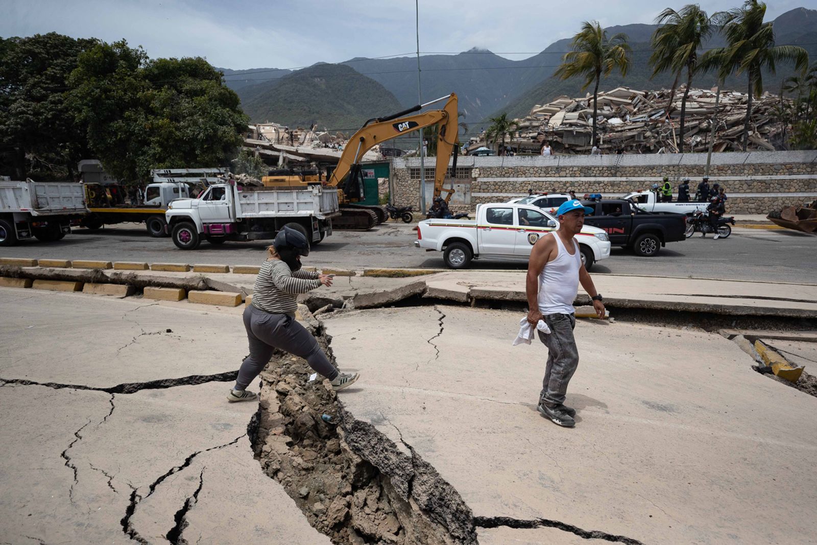 Personas caminan entre las grietas este jueves, que dejaron los terremotos en La Guaira (Venezuela).