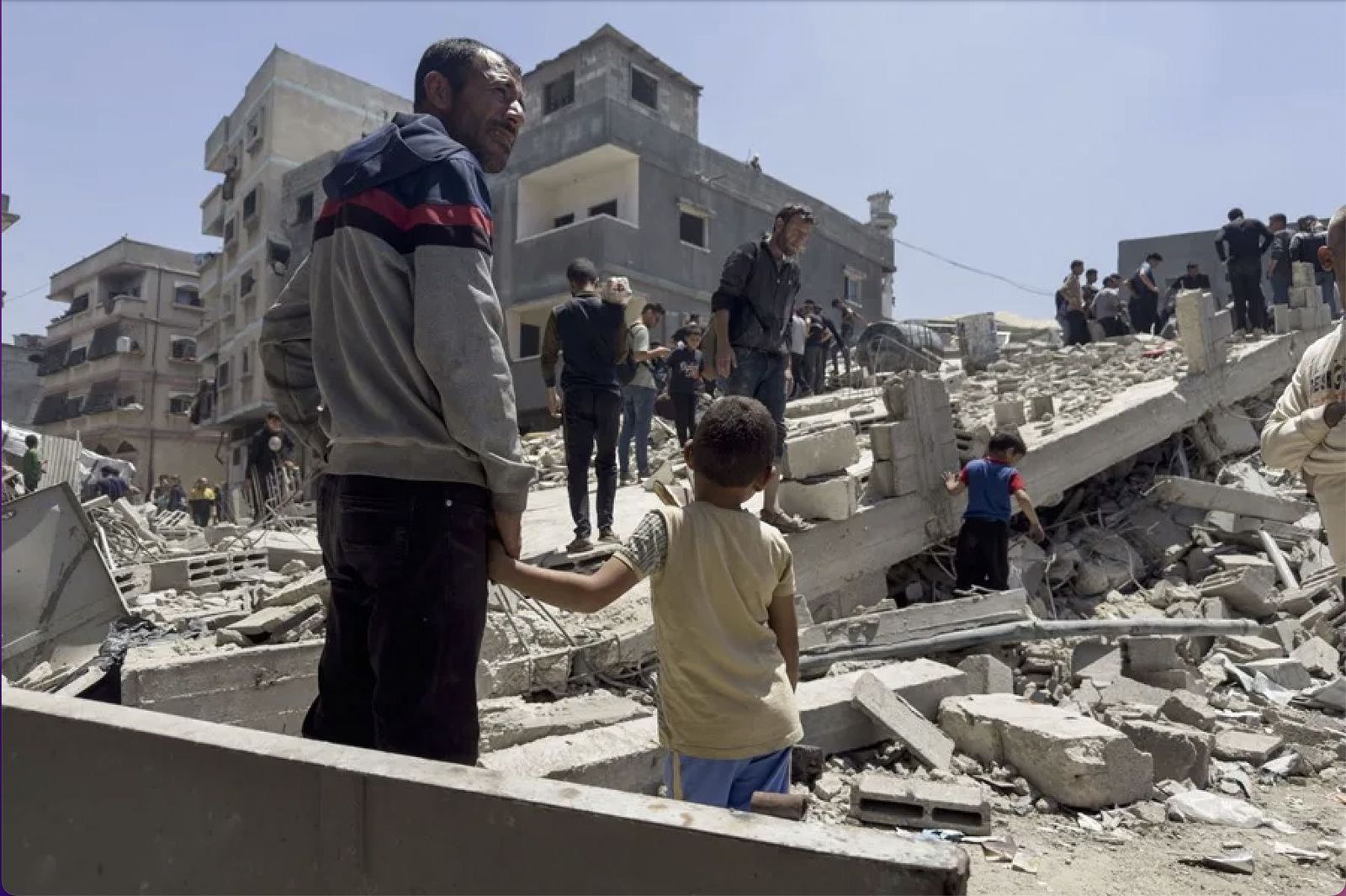 Un hombre y un niño observan los destrozos de un bombardeo en Gaza.