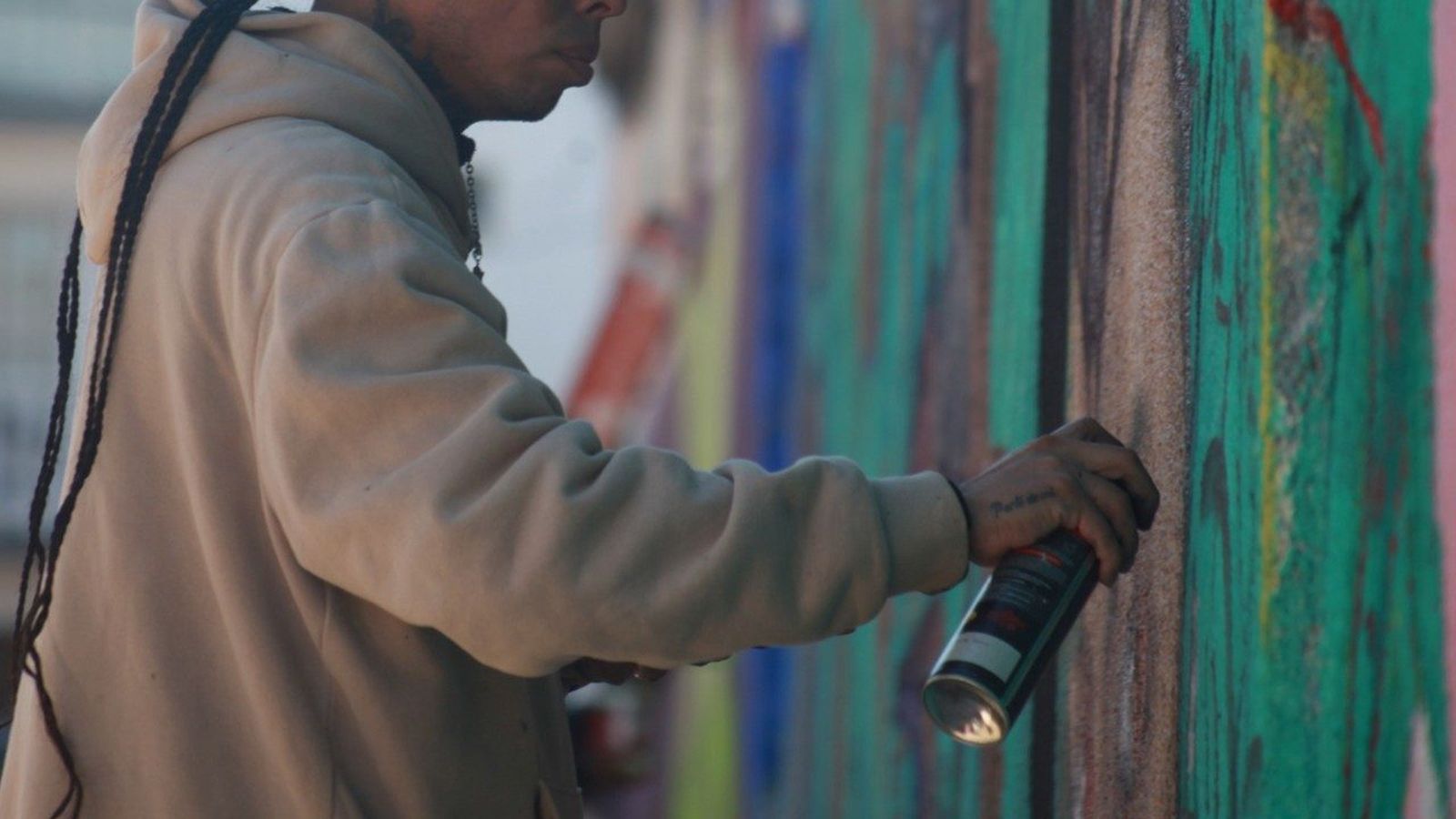 Un joven pinta un mural en la calle