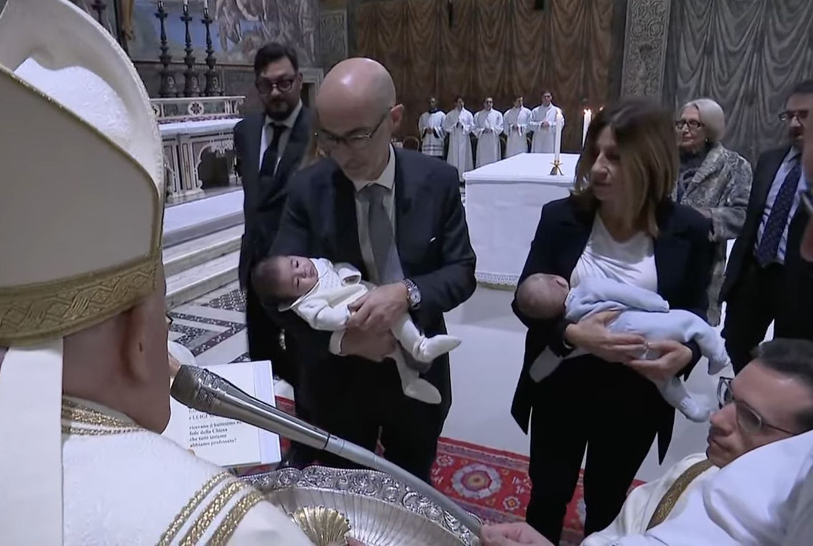 Unos padres presentan a sus dos hijos para ser bautizados por Francisco