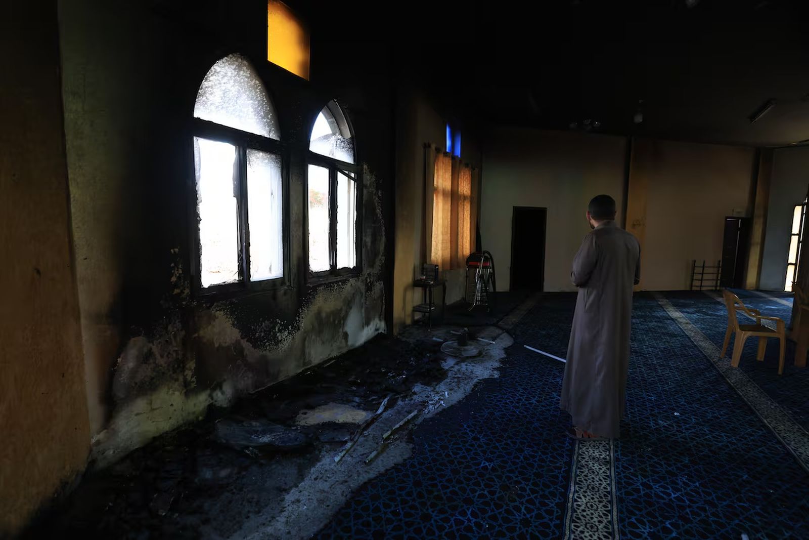 Un hombre observa los daños ocasionados por los colonos israelíes en una mezquita en Der Estya, Cisjordania, en 2025