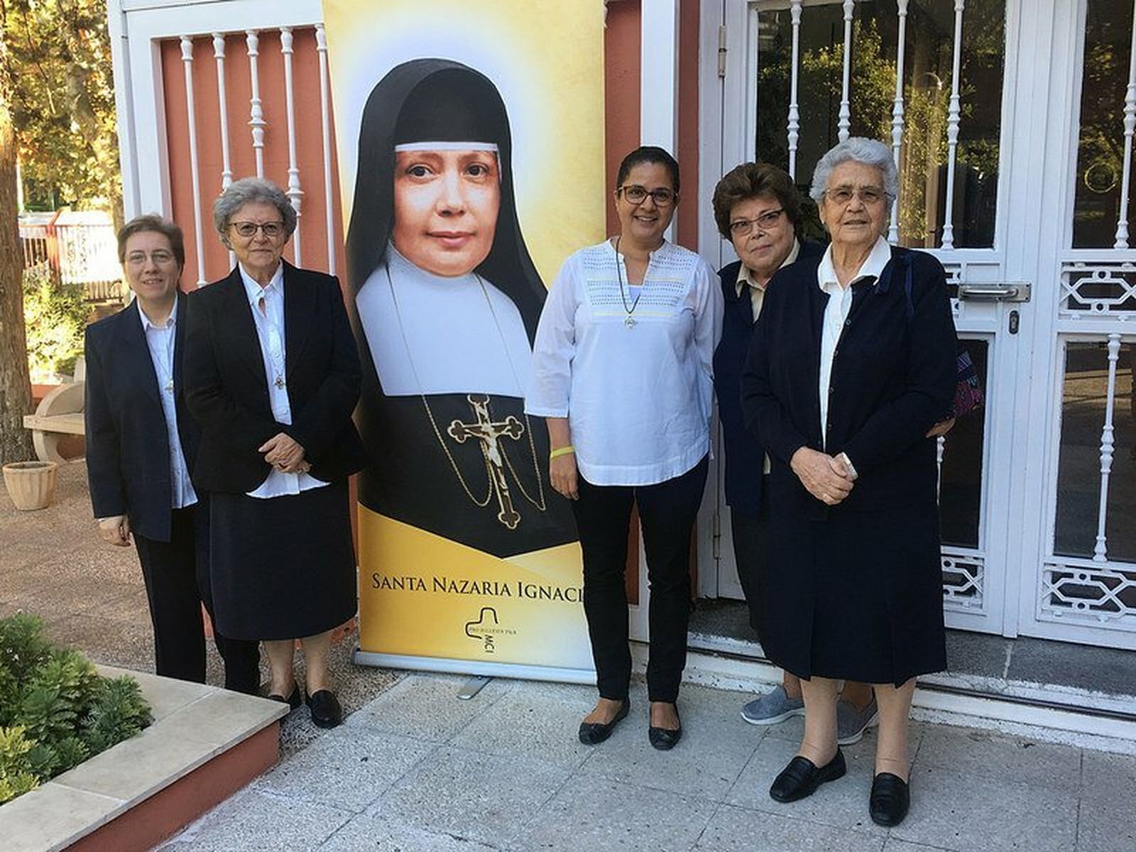 Las Misioneras Cruzadas de la Iglesia, junto a un retrato de la futura santa