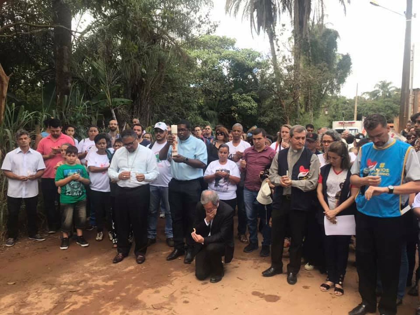 Monseñor Duffé, de rodillas en el centro, reza en el lugar de la tragedia de Brumadinho