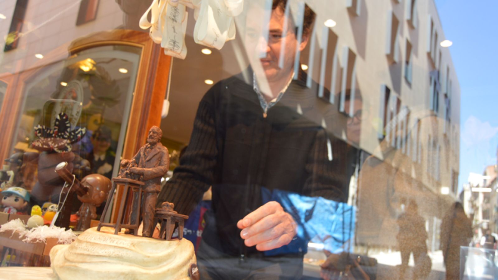 La figura de Gaudí en el escaparate atrae la atención de los transeúntes en Reus.