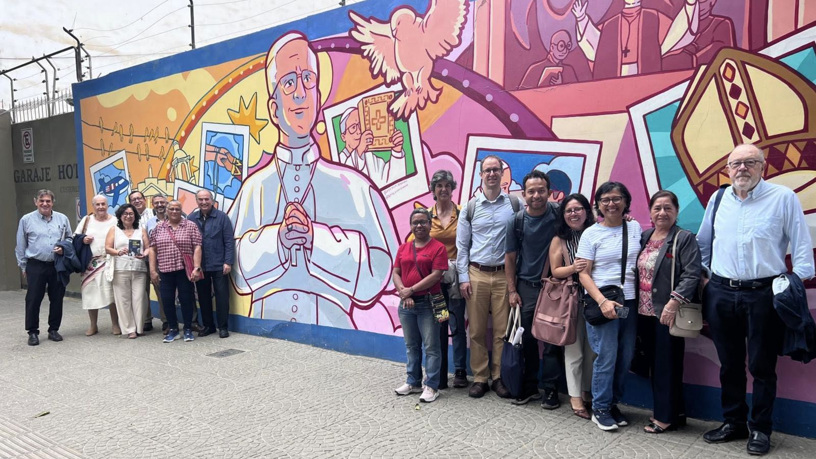 Miembros de Pax Romana ante un mural de Prevost en Chiclayo