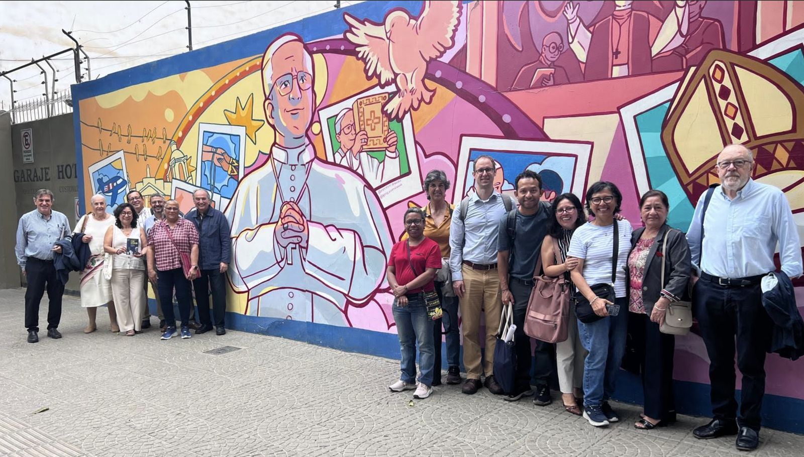 Miembros de Pax Romana ante un mural de Prevost en Chiclayo