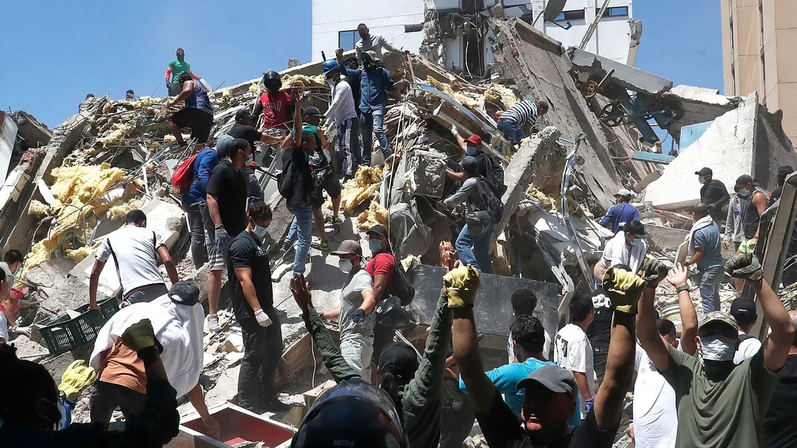 Integrantes del cuerpo de Bomberos de Cali y civiles buscan entre los escombros de edificaciones colapsadas