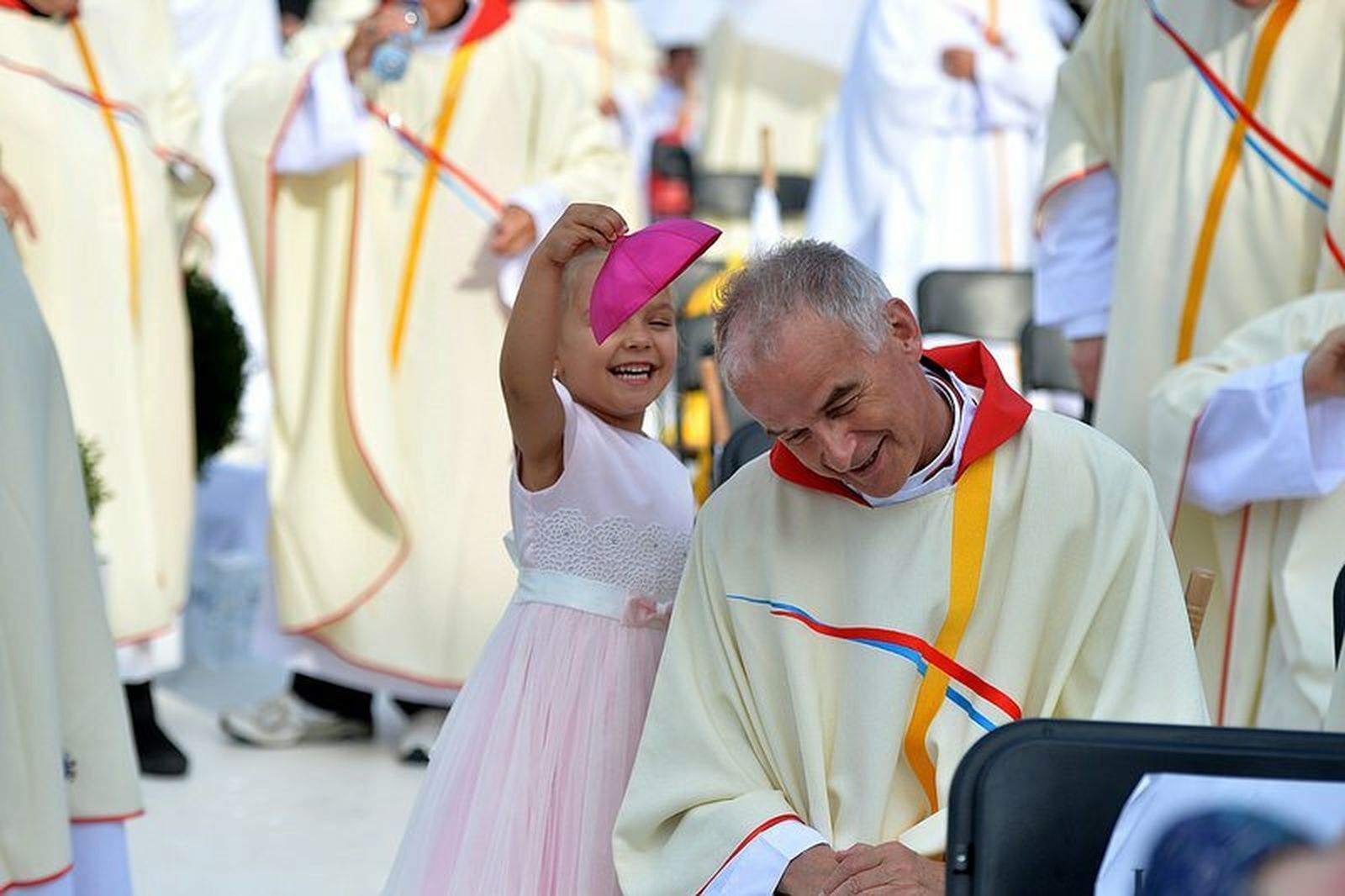 Una niña juega con el solideo de un obispo