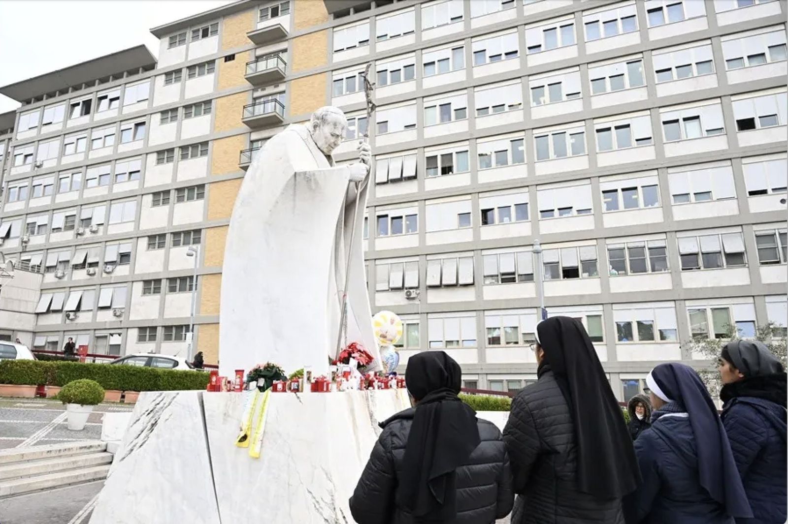 Unas monjas rezan por elFrancisco ante la estatua de Juan Pablo II a la entrada del Gemelli