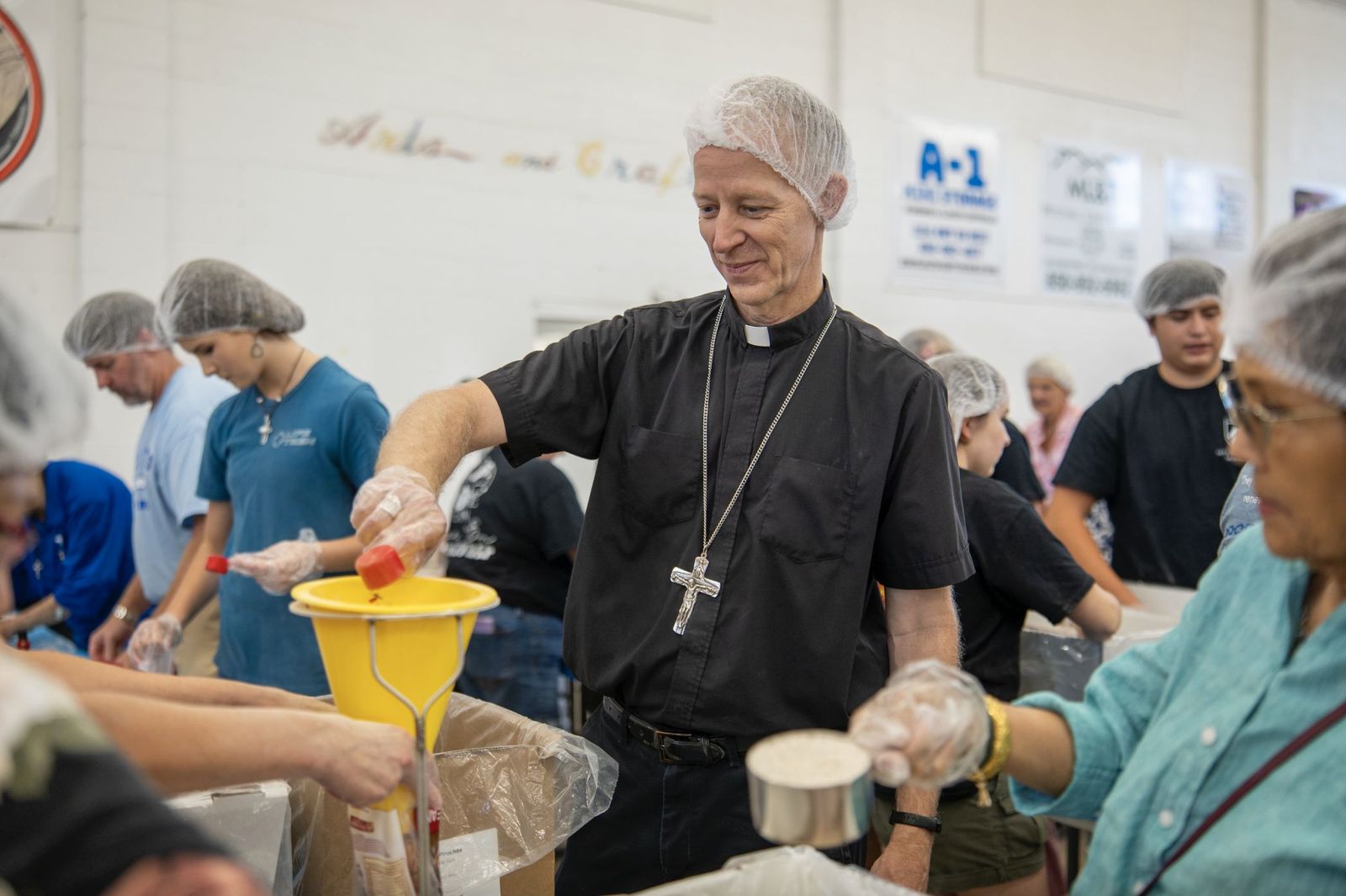 El obispo William Wack ayuda en el envasado de alimentos para repartir a los necesitados