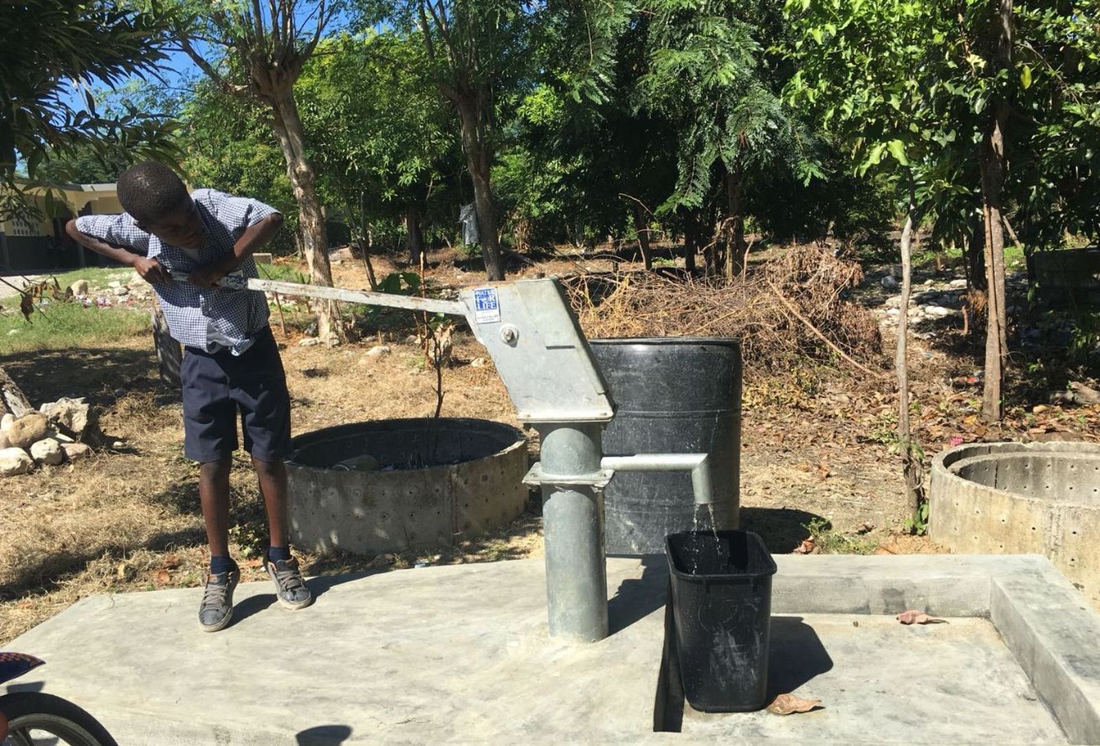 Un niño extrae agua de un pequeño pozo de agua limpia en Jérémie, Haití