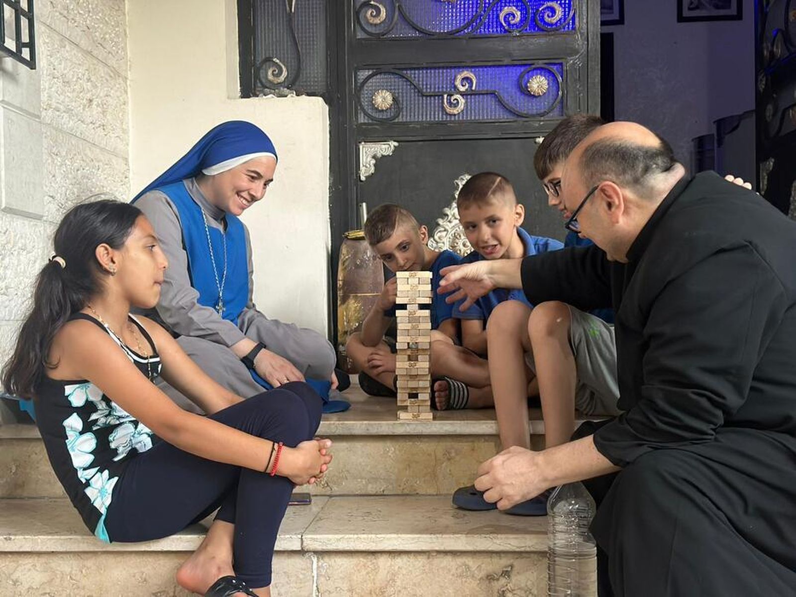 El P. Romanelli y una monja juegan con unos niños acogidos en la parroquia