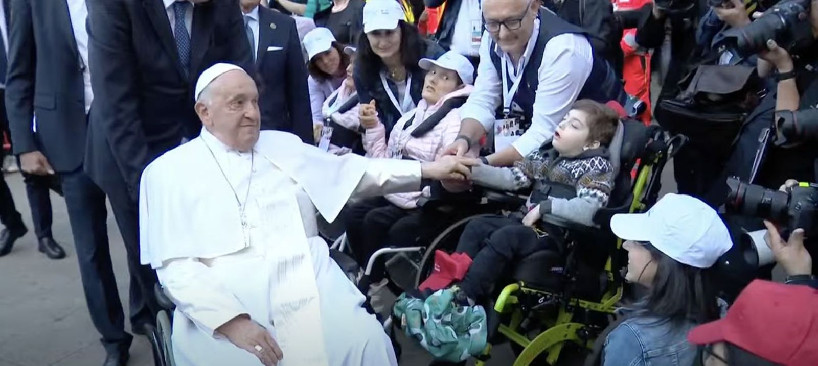 Francisco saluda, desde su silla de ruedas, a un menor discapacitado