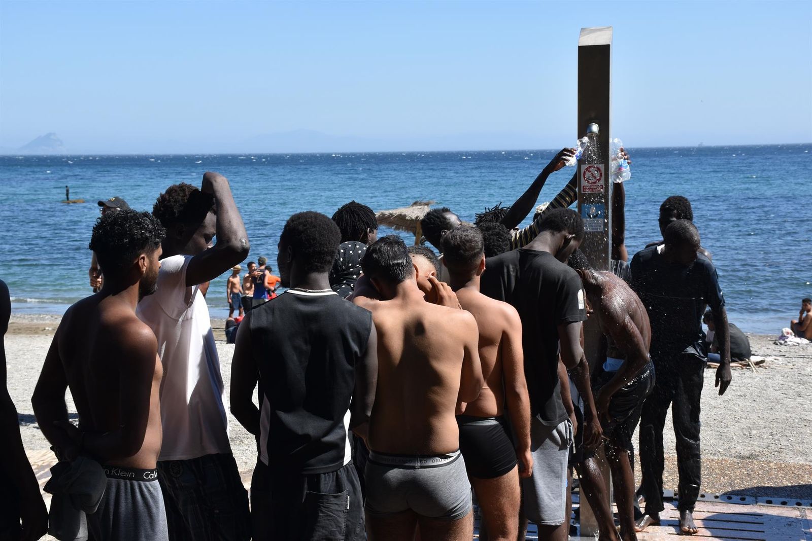 Personas se asean en las duchas públicas de la playa del Trampolín, en Ceuta (España).