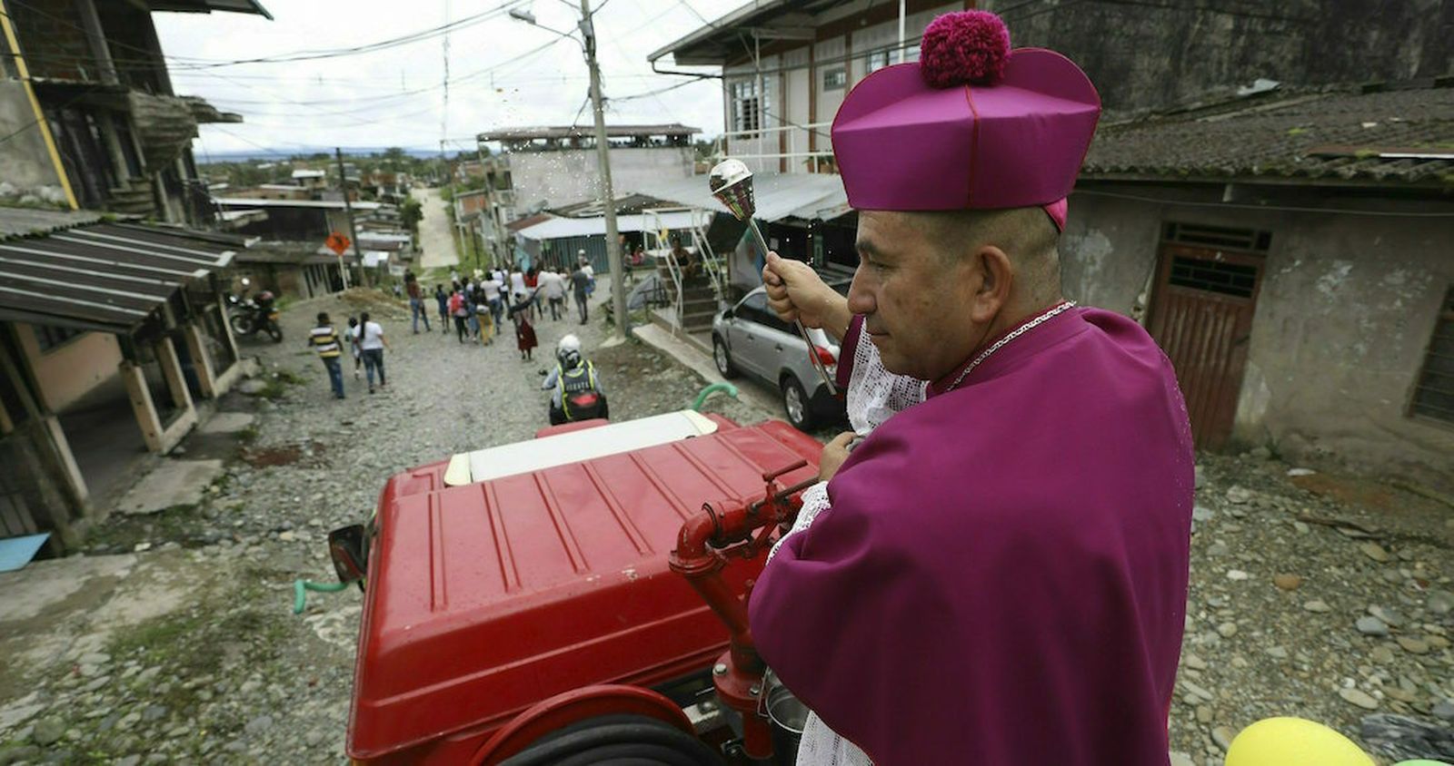 El obispo católico Rubén Darío Jaramillo Montoya rocía agua bendita mientras viaja sobre un camión de bomberos en Buenaventura, Colombia