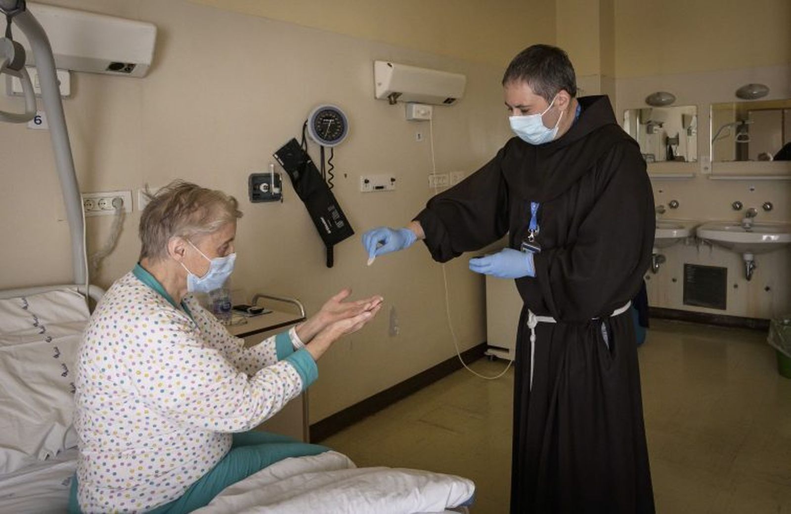 Sacerdote italiano visita a una mujer hospitalizada.