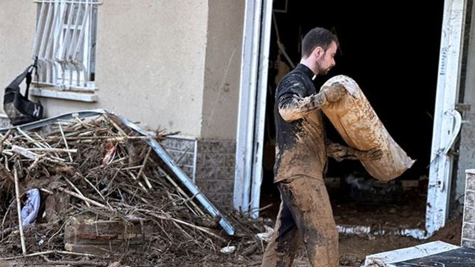 Un capellán limpiando la calle de fango