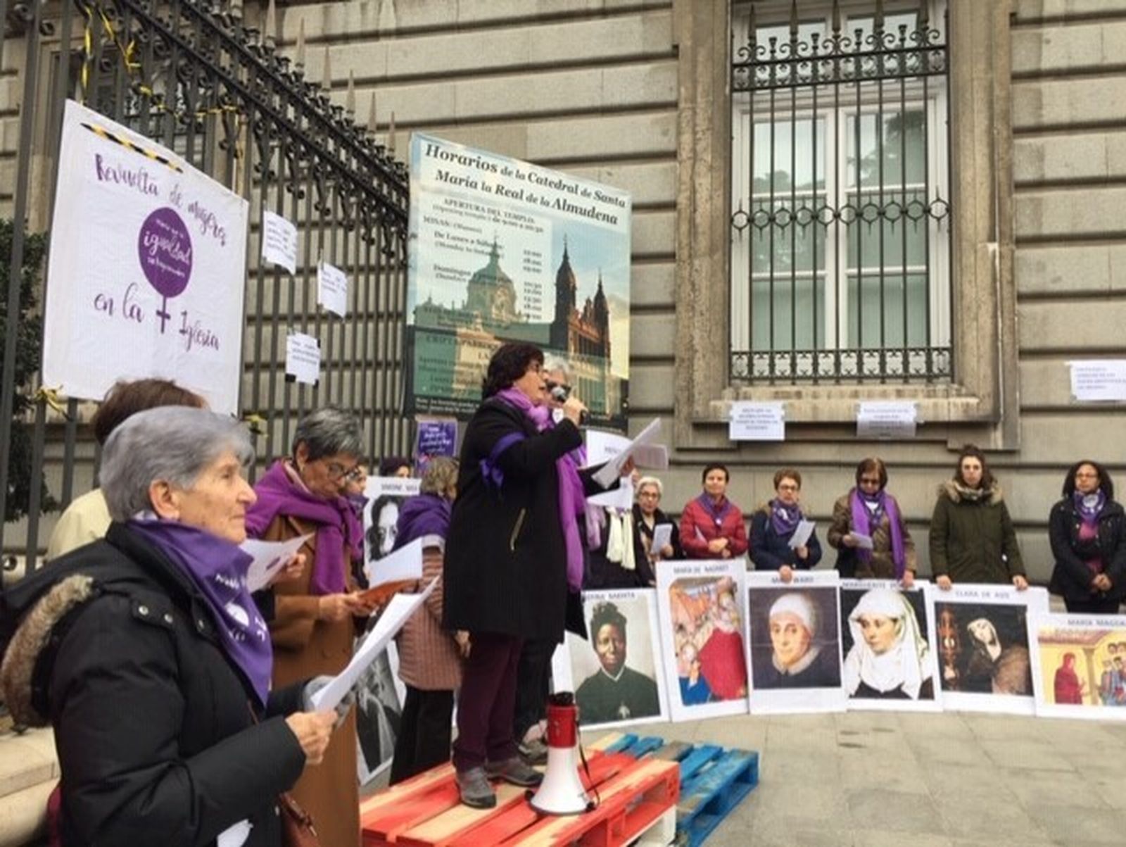 La teóloga Pepa Torres sobre el escenario, rodeada de los carteles de mujeres históricas de Iglesia