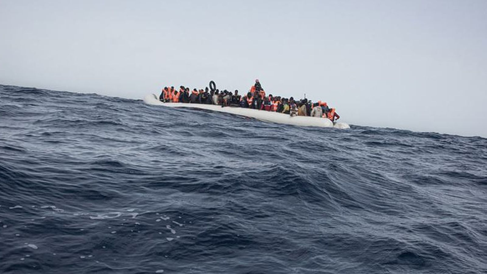 Una embarcación con decenas de personas migrantes a bordo en aguas mediterráneas