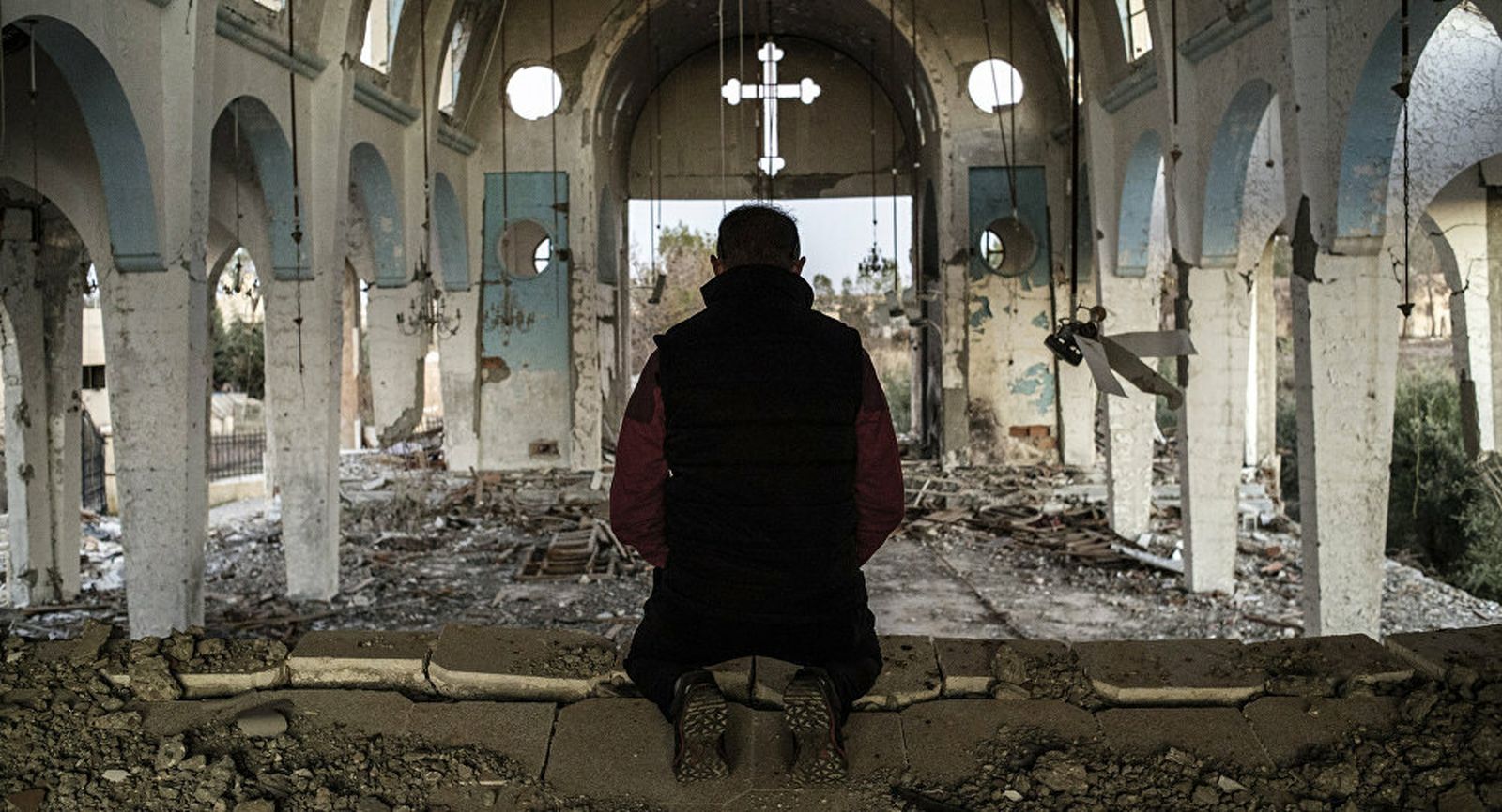 Un hombre reza en una iglesia siria destrozada