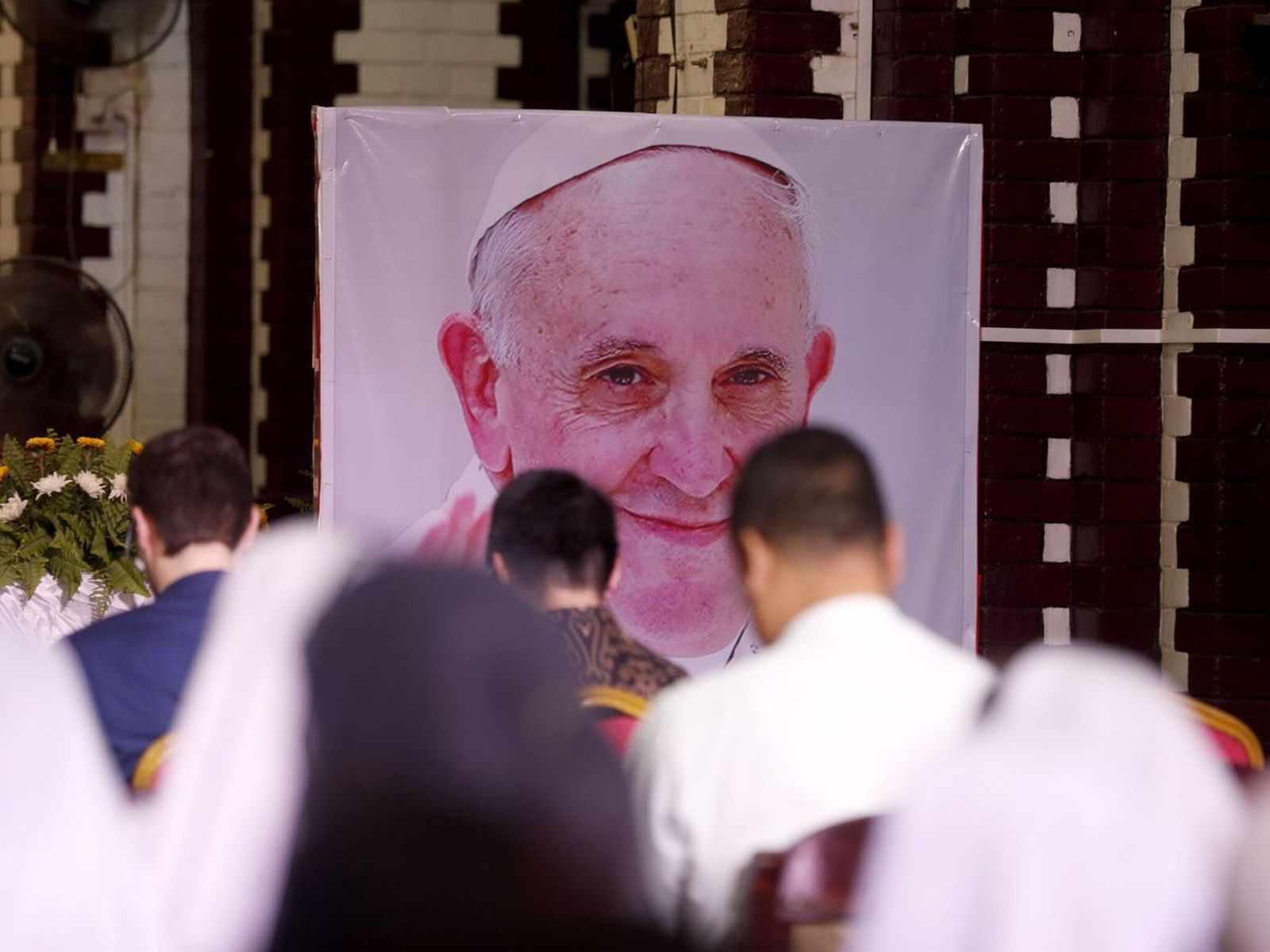 Fieles rezan ante una imagen del Papa