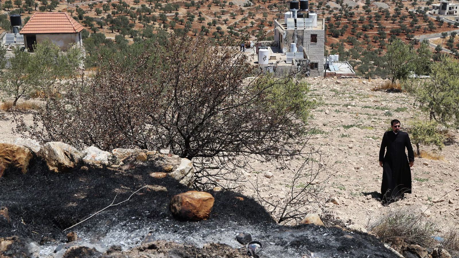 Un sacerdote junto a parte del terreno quemado por colonos judíos junto a la iglesia de San Jorge de Taybeh (Cisjordania).