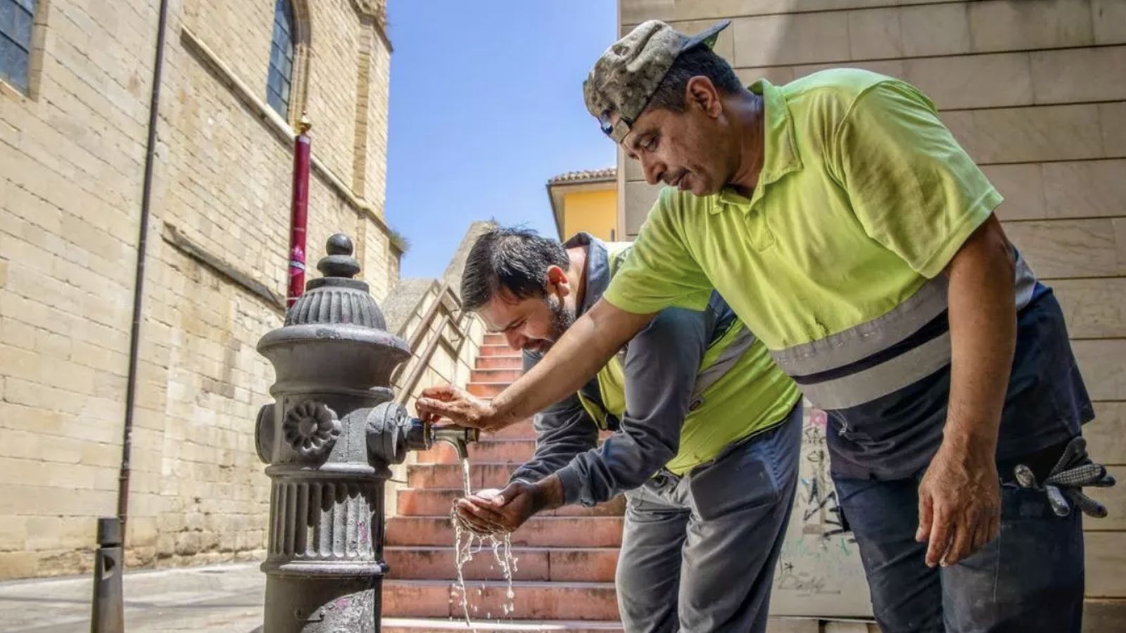 Dos trabajadores se hidratan en plena calle