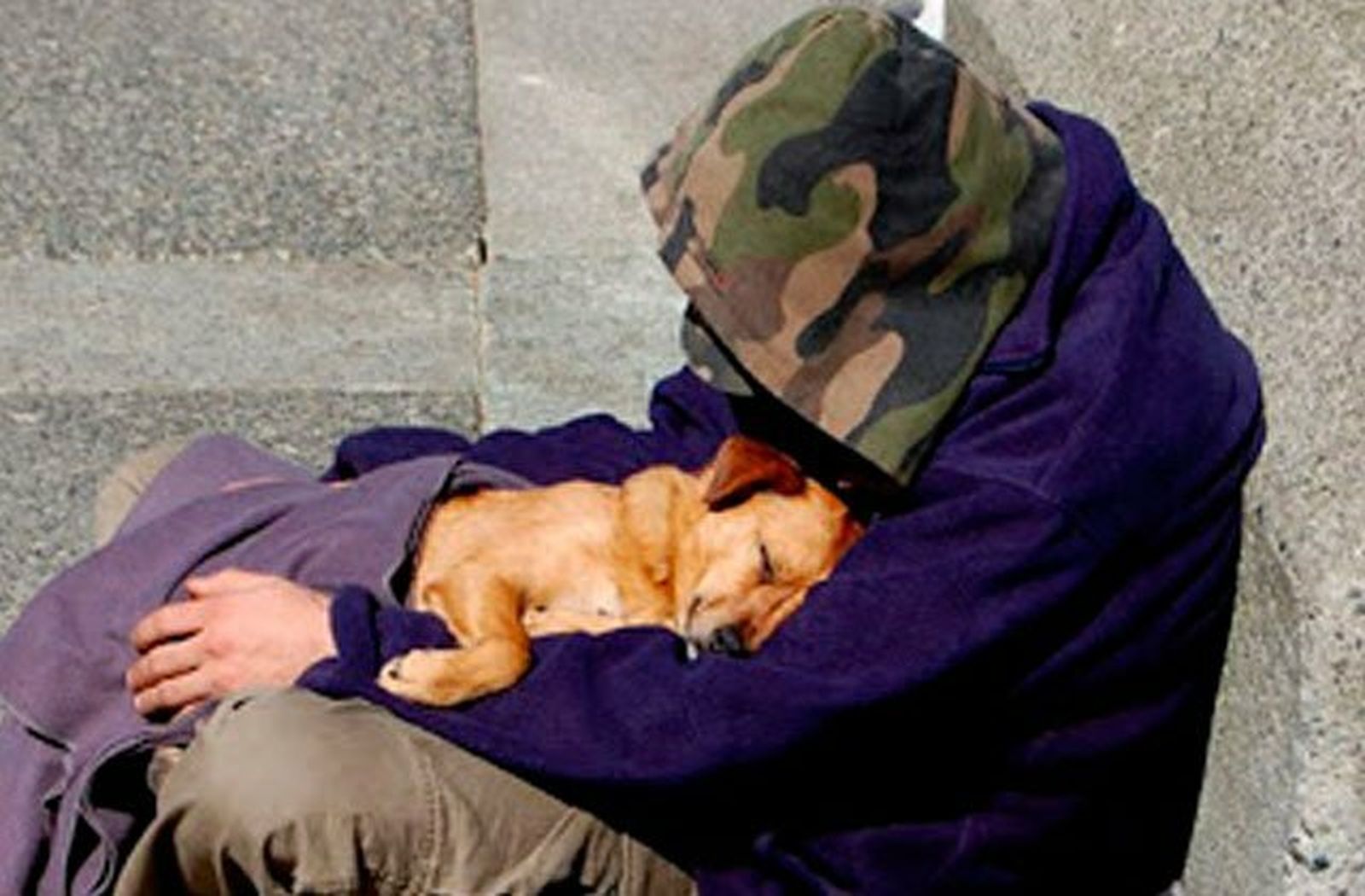 Un persona sin techo cobija a su perro