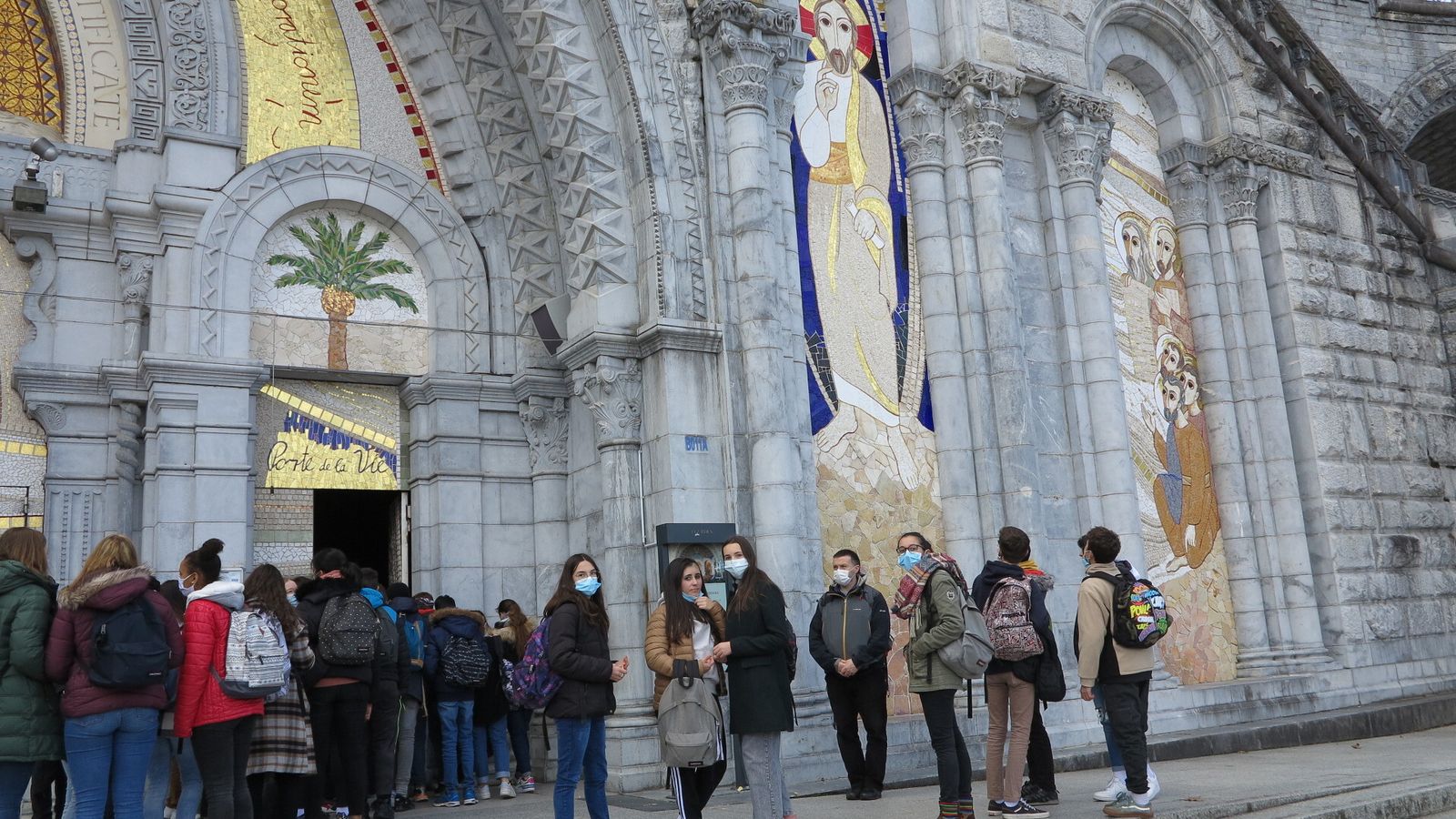 Unos jóvenes ante la fachada de la basílica, adornada con los mosaicos de Rupnik