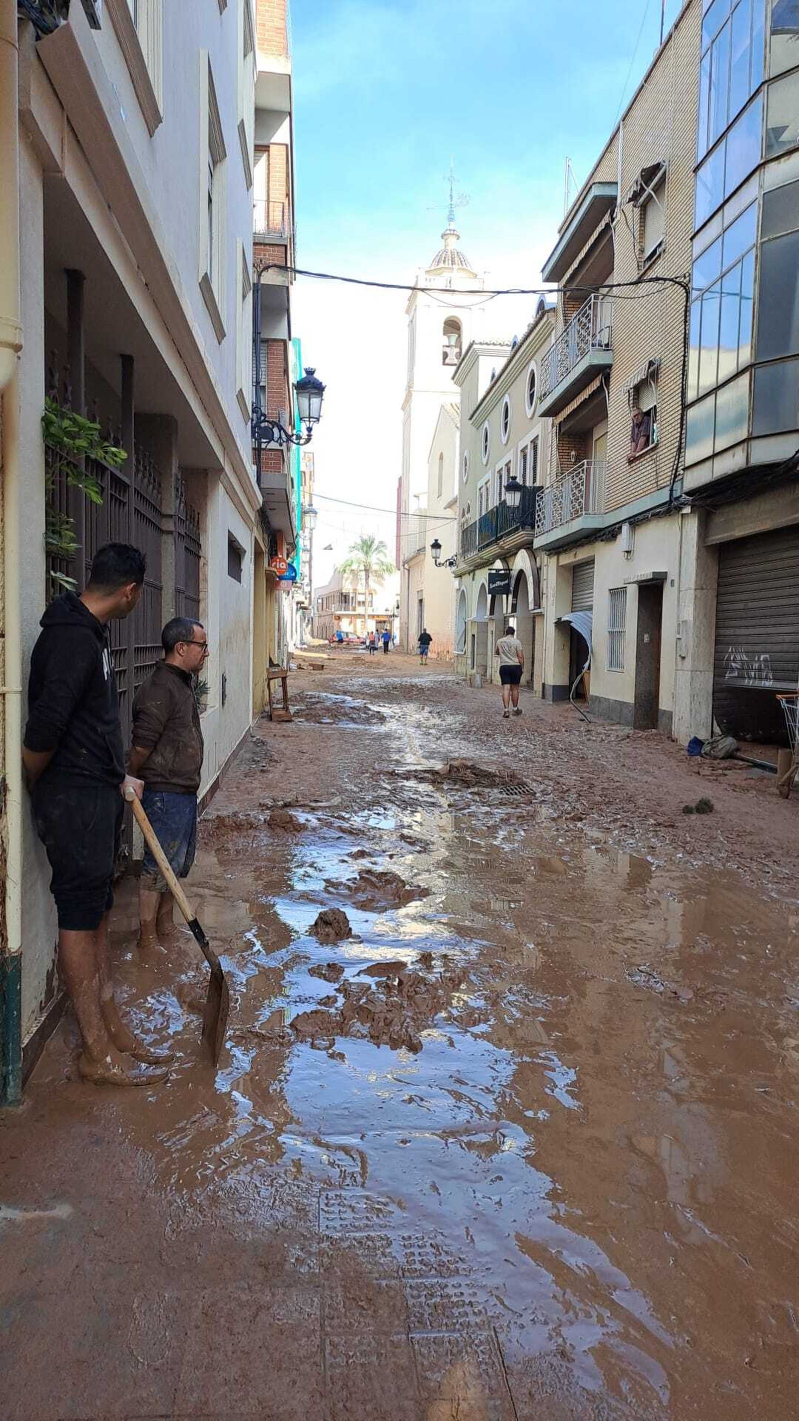 Voluntarios limpiando el fango junto a la iglesia