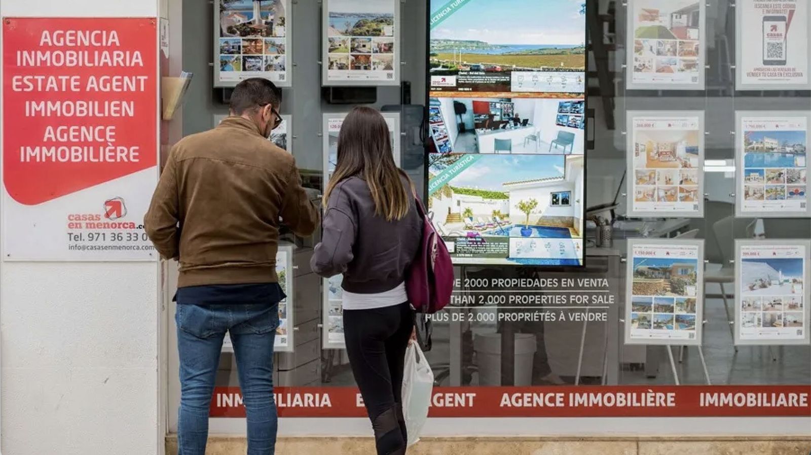 Una pareja ante una agencia inmobiliaria