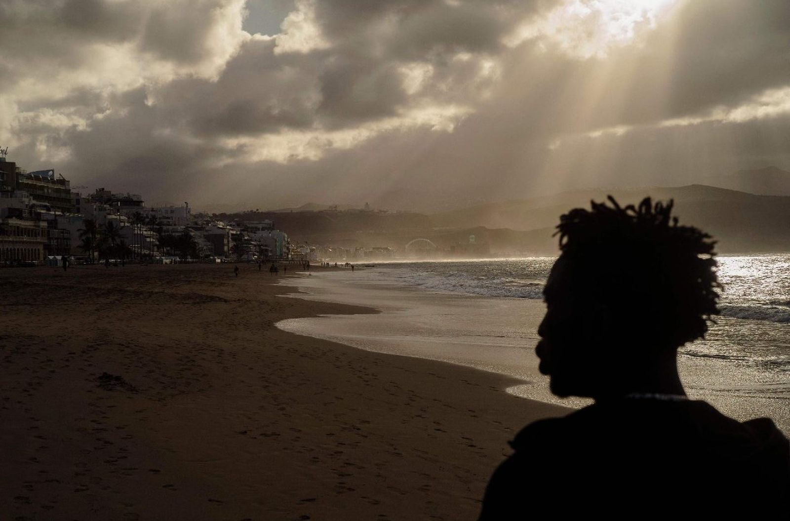 Un ghombre pasea por la Playa de Las Palmas, España, una semana después de llegar de Gambia