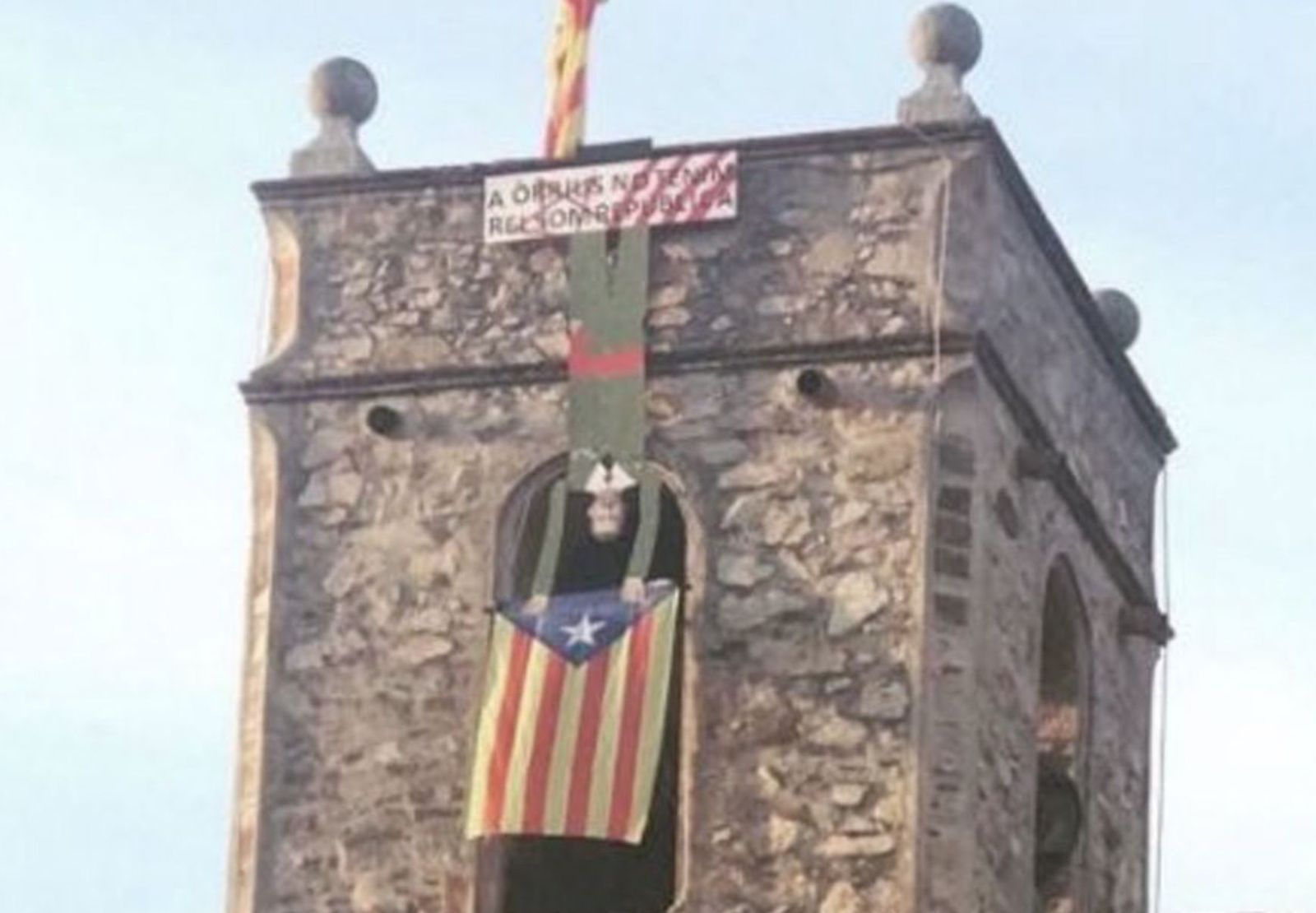 Campanario con una estelada y la figura del rey boca abajo