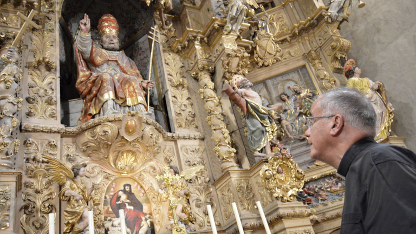 El párroco, ante el retablo barroco.
